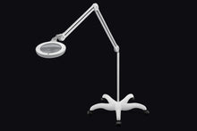 Load image into Gallery viewer, Omega 5 magnifying lamp with floorstand attached, against a black background. 
