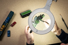 Load image into Gallery viewer, Image of magnifying lamp being used to paint a green miniature train.
