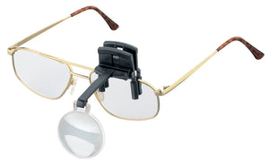 Monocular (circular) lens on black arm and clip, attached to glasses.