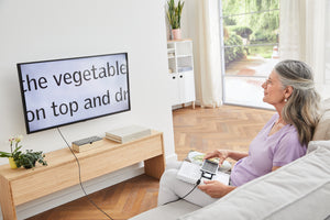 Woman using Smartlux DIGITAL as a screen reader, to read a book on a TV