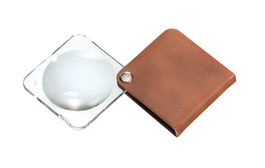 Circular magnifier inside clear square setting, with attached fold-out light browncase