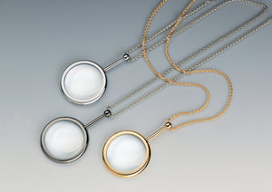 Small pendant style, circular magnifiers in gold and chrome with matching neck chains.