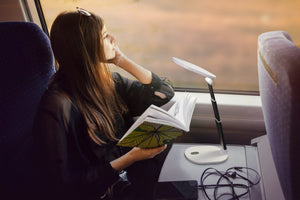 Woman using Daylight's Foldi Go on a train to read.