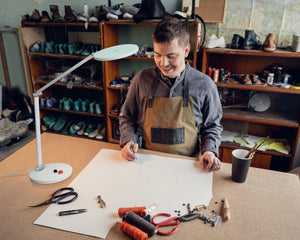 Man using Daylight's Tricolour lamp in a workshop to see design on paper.